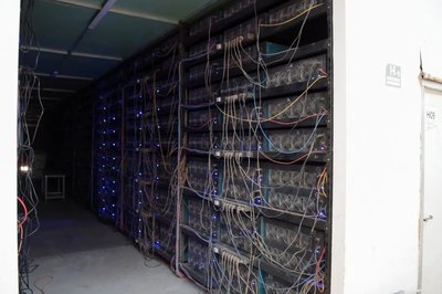 An aerial view of a large-scale cryptocurrency mining farm, showing rows of ASIC miners